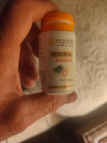 Customer's hand holding the white bottle of Serenoa Repens supplement with an orange cap.