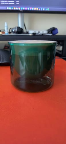Customer's green FLUR Latte XL glass sitting empty on an orange desk surface.