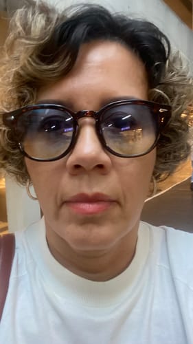 Reviewer vestindo o Óculos de Sol Jurerê de armação escura, demonstrando o ajuste leve no rosto.