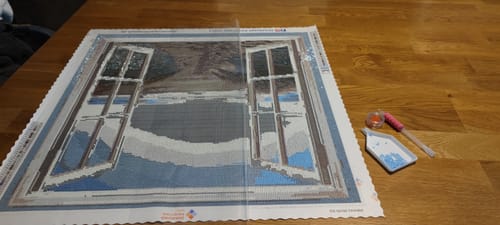Kunden-Diamond-Painting Meerblick-Leinwand mit Motiv von Fenstern zum Meer, daneben Stift und Steinchenablage.