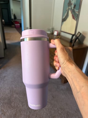 Reviewer's hand holding a lavender Thicc Buddy 40oz insulated mug indoors.