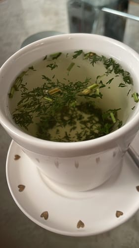 Customer's Beifuss einjährig Bioproduct in einer Tasse heißem Tee, der die getrockneten Kräuter im Wasser zeigt.