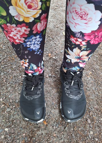 Reviewer's black Vaistoa Lento paljasjalkajuoksukengät outdoors while wearing floral leggings.