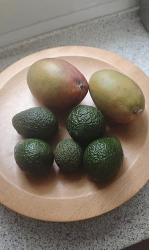 Customer's Osteen Mango und Avocados auf einem runden Holzteller