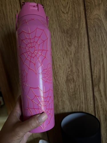 Customer's pink Bottle Buddy cup with a heart-shaped spider web pattern, held by a hand.