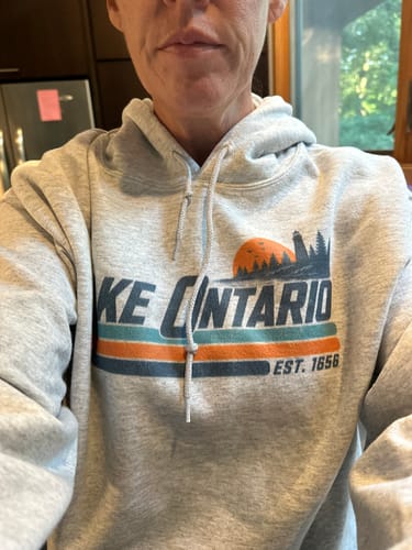 Customer's gray Lake Ontario Retro Stripe Hoodie featuring a graphic of a sun, lighthouse, and forest.