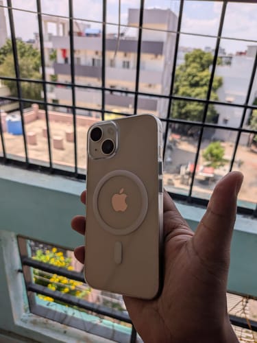 Customer's Anti Yellow Magsafe Clear Case on an iPhone 14, held in hand against a balcony railing background.