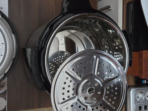 Customer's metallic Novio SteelCook multicooker with the lid open and a stainless steel steam rack inside.