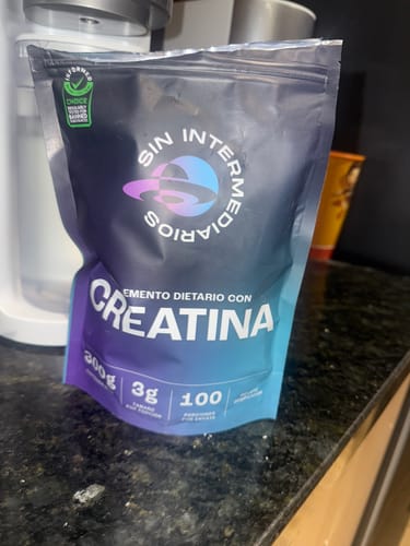 Customer's Creatina Monohidratada pouch with blue and purple packaging on a dark surface.