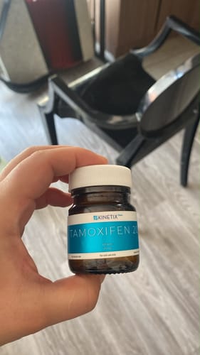 Reviewer's hand holding a brown plastic bottle of Tamoxifeno 20 mg by Kinetix Pharma.