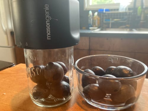 Customer's Mason Genie Vacuum Sealer Kit in black attached to a glass mason jar filled with small produce.