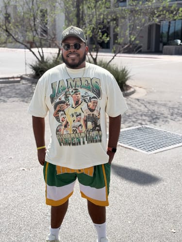 Customer's LeBron HS Tee worn with green and yellow shorts, featuring basketball graphics in an outdoor setting.