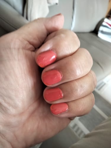 Reviewer's hand showing applied Red Stilettos UV Gel Nail Wraps in a vibrant orange-red shade.