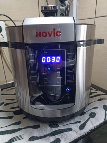 Customer's Novio SteelCook multicooker with digital display illuminated, resting on a kitchen towel.
