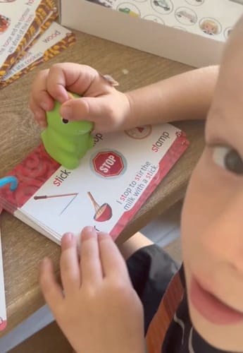 Child tapping a sticker book with Rexi.