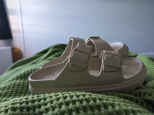 Customer's beige HappyFlops sandalen met riempjes op een groene wafelstof deken.