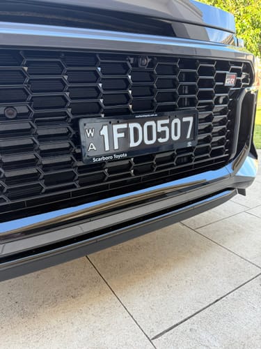 Reviewer's installed OEM Plinth Delete Kit on a black Toyota RAV4 GR SPORT, showing a clean, centered license plate.