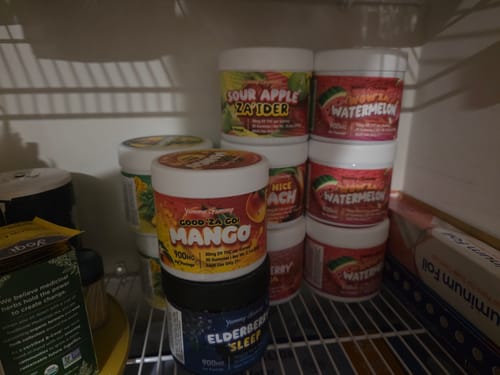 Customer's collection of Yummy Gummy jars in various flavors, including Mango and Watermelon, stored on a shelf.