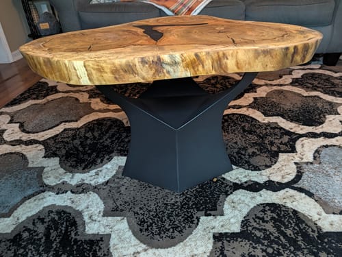 Customer's 16-inch Namu coffee table base in black supporting a natural wood tabletop on a patterned rug.