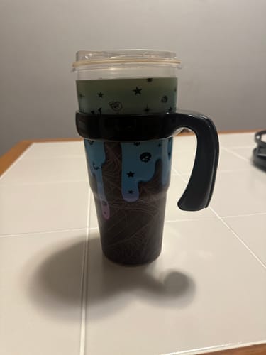 Customer's black To-Go Buddy handle attached to a patterned travel tumbler sitting on a white tiled surface.