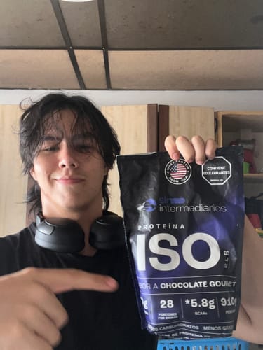 Reviewer smiling and pointing at a bag of Proteína Aislada ISO Chocolate Gourmet.