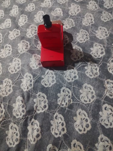 Customer's Attracione Men perfume bottle and red box placed on a patterned bedspread.
