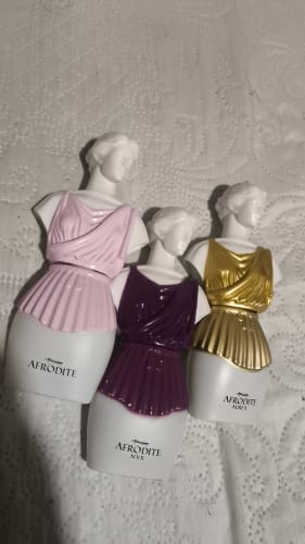 Reviewer's three Kit Afrodite perfume bottles, shaped like white female busts with pink, purple, and gold bodices.