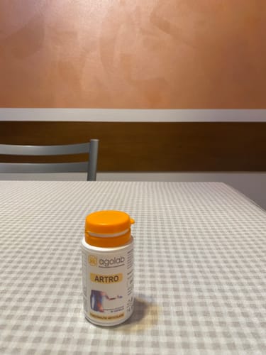 Il flacone di Agolab Artro su un tavolo a quadri, descritto in una recensione positiva per il supporto articolare.