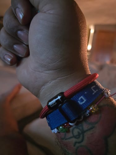 Customer's red paracord R.E.D. bracelet worn on wrist alongside other bracelets.