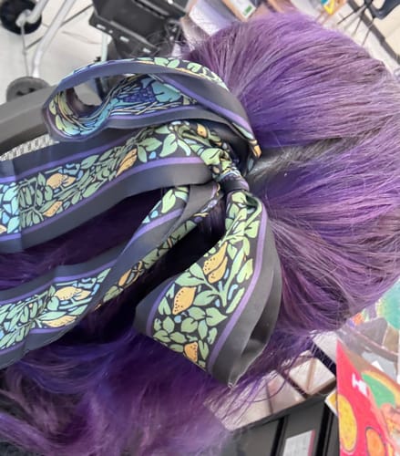 Customer's Sicily Skinny Scarf tied in a bow in vibrant purple hair
