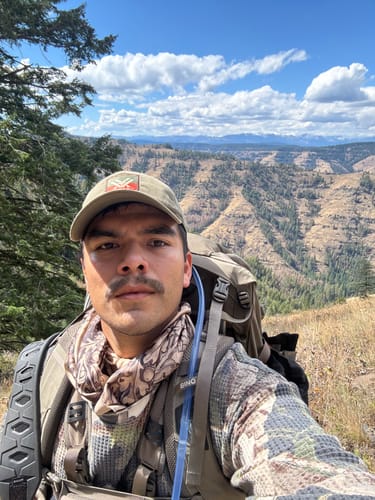 Customer's Elk Silky Scarf worn around the neck while hiking in a mountainous landscape.