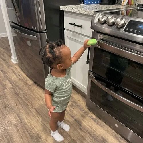 Toddler tapping Rexi on a sticker in the kitchen.