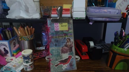 Customer's Steel Arch Clip holding the pages of an audio journal flat on a cluttered desk.