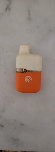 Customer's orange and white ROLLZ THC-A vape device on a marble surface.