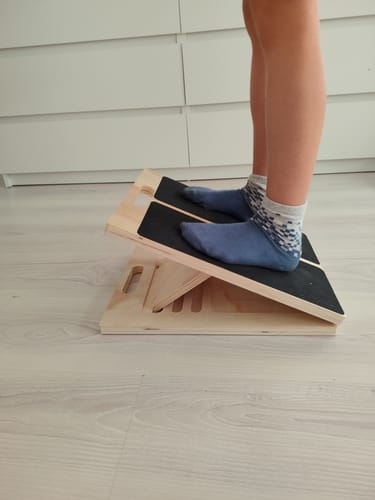 Customer's SlantCore adjustable calf stretching board being used by a person standing in blue socks.