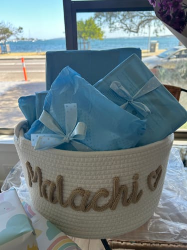 Customer's Baby Knits personalized white cotton basket with Malachi and heart icon on a table.