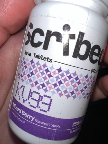Customer's hand holding a white bottle of Scribed KV99 Mixed Berry Kava Tablets.