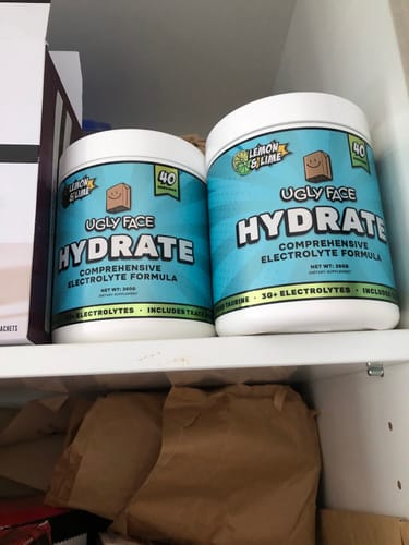 Customer's two large tubs of UGLYFACE HYDRATE lemon and lime electrolyte formula sitting on a pantry shelf.