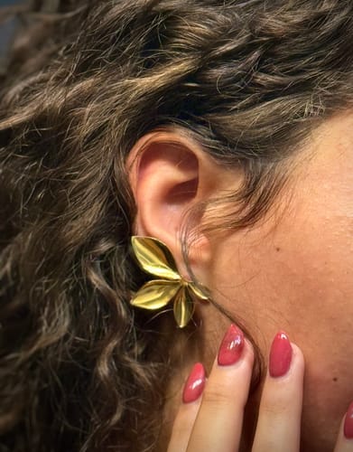 Customer's gold leaf-shaped earring worn on the earlobe