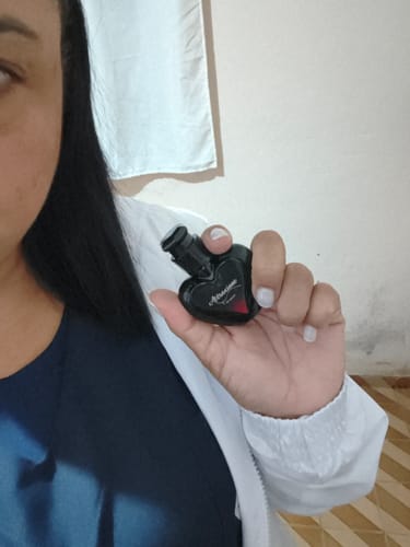 Customer's hand holding a small, heart-shaped black bottle of Perfume Attracione Sensual.