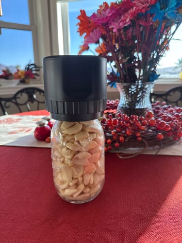 Customer's black Mason Genie Vacuum Sealer Kit attached to a glass jar filled with peeled garlic cloves.