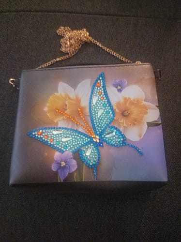 Customer's completed Diamond Painting Schultertasche decorated with a bright blue butterfly and yellow flowers.
