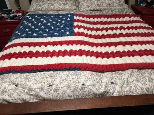 Customer's patriotic Hugs Flag Blanket with a plush, textured design spread out over a bed.