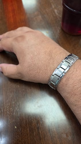 Customer's Iron Man Armor Titanium Magnetic Bracelet worn on their wrist against a dark wooden surface.