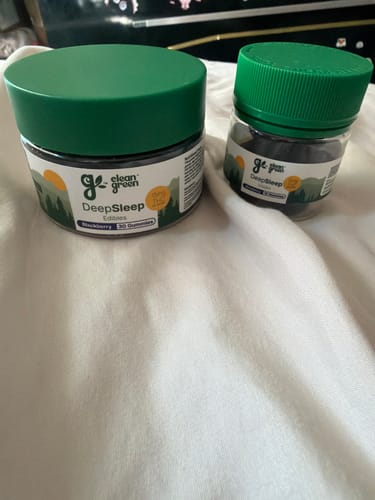 Customer's two round DeepSleep Gummies jars with green lids placed on a white cloth surface.
