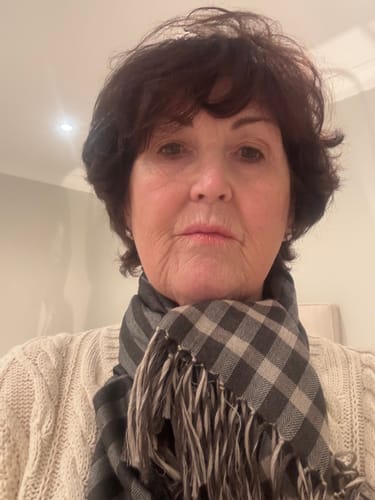 Customer's Begg & Co grey gingham and stripe cashmere blend wrap worn around the neck.