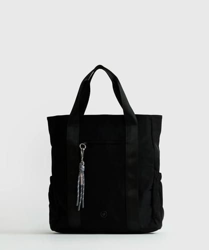 Customer's black Mochila Notebook Parka backpack with thick straps and a colorful keychain hanging from the front zipper.