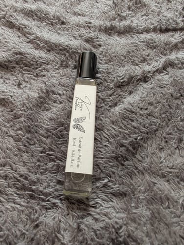 Customer's Kiage 109 Extrait de Parfum travel bottle resting on a textured gray surface.
