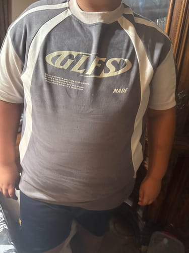 Customer's grey and cream GLFS T-shirt worn by a person, showing the oval graphic logo on the chest.