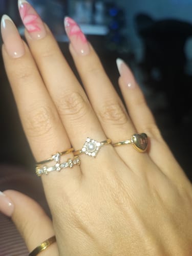 Reviewer's hand wearing the Pearl & Crystal Eternity Ring alongside other gold rings, appearing shiny and clean.